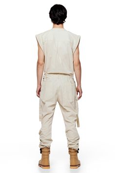 Jonny Cota takes on the summer suit with this season's Sleeveless Canvas Jumpsuit, crafted from soft baby canvas with cargo patch pockets and gun metal hardware detailing throughout. — Cargo patch pockets— Gun metal snaps— Zip closure at center middle— 100% baby canvas suedeSIZE + FIT— Loose, relaxed fit— Adjustable d-ring belt at waist— Model is 6’0 and wearing a size L CARE— Dry clean recommended Utility Style Sleeveless Jumpsuits And Rompers With Pockets, Sleeveless Cotton Utility Jumpsuits And Rompers, Khaki Utility Jumpsuits And Rompers For Summer, Summer Cotton Jumpsuits And Rompers With Belt Loops, Utility Cotton Jumpsuits And Rompers In Cargo Style, Utility Cotton Cargo Jumpsuits And Rompers, Utility Cotton Jumpsuits And Rompers With Multiple Pockets, Utility Style Cotton Jumpsuits And Rompers With Cargo Details, Utility Relaxed Fit Jumpsuits With Cargo Pockets