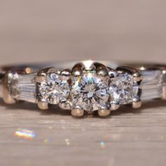 a three stone diamond ring on a wooden surface