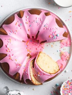 a cake with pink frosting and sprinkles on it sitting on a plate