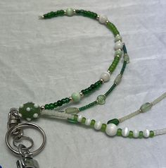 "This keychain relies on 'less is more' the head bead is a beautiful green glass bead with white knobby effect. green is the main color with white as accent.  the four strands are composed of green and white beads including cats eye & heart beads Beautiful handmade beaded keychain. Multiple strands, each one it's own little work of art as well as an original- no two are identical. Hand strung using quality beads, glass & crystals, pearls, metal beads, gemstones and quality findings. Individual s Green Keychain As A Gift, Green Dangle Beads For Gifts, Green Glass Beaded Chain Jewelry, Green Keychain With Key Clip As Gift, Green Beaded Keychain, Green Keychain With Key Clip For Gift, Green Multi-strand Beaded Jewelry, Beaded Car Charms, Green Tiny Multi-strand Beads