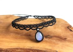 a black lace choker with a blue stone hanging from it's side on a wooden board