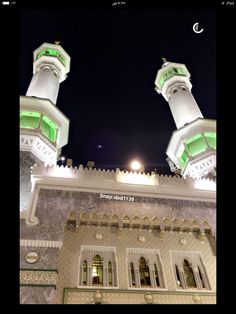 two tall white buildings sitting next to each other in front of a building at night