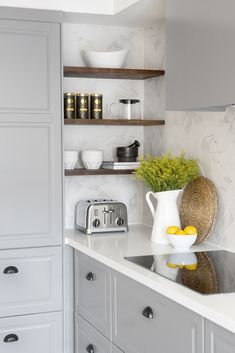 a kitchen with white cabinets and shelves filled with dishes on top of the counter tops