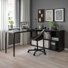 a desk with a laptop on top of it in front of a window and bookshelf