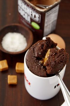 a chocolate dessert in a white cup next to some sugar cubes and an egg