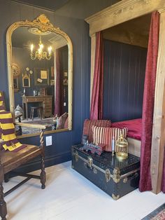 a bedroom with blue walls and red drapes on the canopy bed is decorated in an antique style