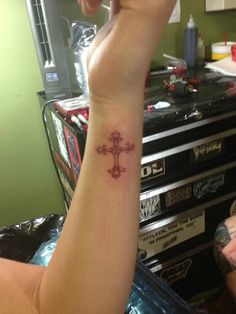 a person with a cross tattoo on their arm