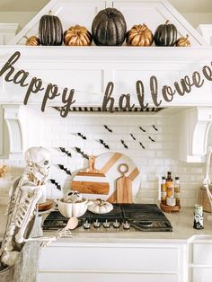 a kitchen decorated for halloween with pumpkins and skeleton decorations on the shelves above the stove