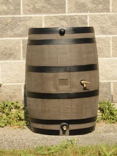 a wooden barrel sitting in the grass next to a brick wall with a door on it