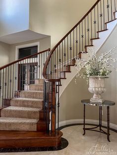 a vase with flowers sitting on top of a table next to a stair case in a home