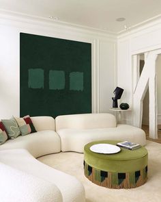 a living room with white furniture and green accents