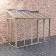 a small wooden greenhouse on a brick wall