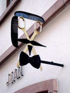 a pair of scissors hanging from the side of a building with a bow tie on it