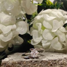 two wedding rings sitting on top of a rock next to white hydrangea flowers