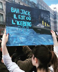 a woman holding up a sign in front of a group of people on the street