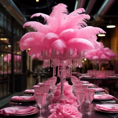 the table is set with pink feathers and place settings