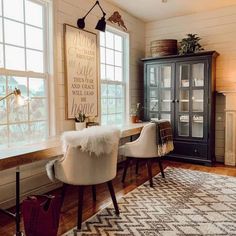 a living room with two chairs and a rug in front of a window that has a sign on it