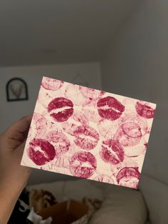 a person holding up a piece of paper with lipstick prints on it