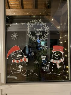 a frosted glass window with two snowmen and a christmas wreath on the front