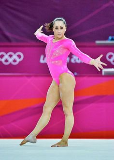 a female figure in a pink leotard performing on the ice rink at an olympics event