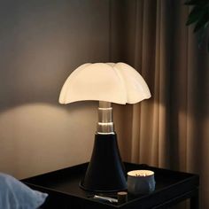 a table lamp sitting on top of a night stand next to a window with curtains