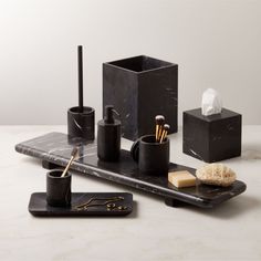 black marble bathroom accessories including soap, toothbrushes and other items on a white table