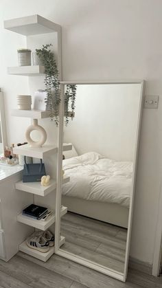 a bedroom with a large mirror on the wall next to a white bed and nightstand