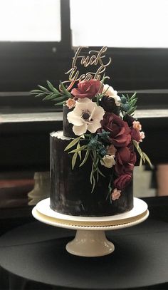 a black and white cake with red flowers on top is sitting on a table in front of a piano