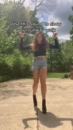 a woman standing in the middle of a road with her arms up and legs spread out