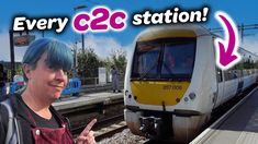 a woman with blue hair standing in front of a train on the tracks and pointing at her finger