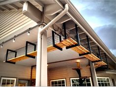 a white house with metal railings and lights on the front porch, under a cloudy blue sky