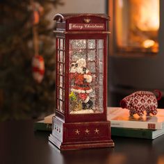 a red phone booth sitting on top of a table next to a christmas ornament