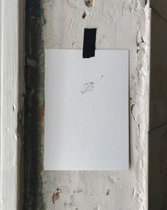 a piece of paper hanging on the side of a wall with some paint peeling off it