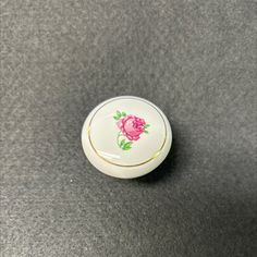 a white and pink flowered cabinet knob on a black surface with gold trimming