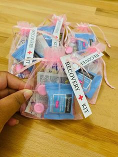 a person is holding some pink items in a clear bag on a wooden table with tags attached to it