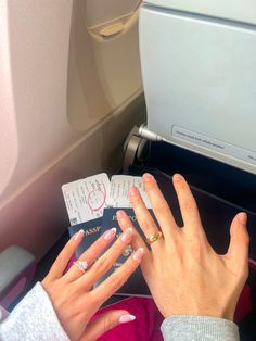 a woman's hands with manicures on her nails reading a book in an airplane