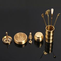 an assortment of brass items on a black surface with reflection in the middle, including brushes and spoons