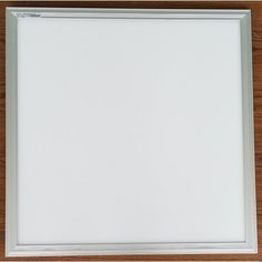 an empty white frame on a wooden surface