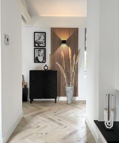 a room with white walls and wood flooring next to a black cabinet in the corner