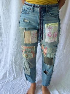 a woman in yellow shirt and jeans with patches on her legs standing next to white backdrop