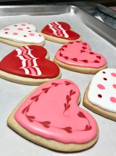 decorated heart shaped cookies sitting on top of a cookie sheet