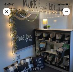 a room with bookshelves and lights on the wall, along with decorative pillows