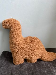 a brown stuffed animal laying on top of a black blanket next to a white wall