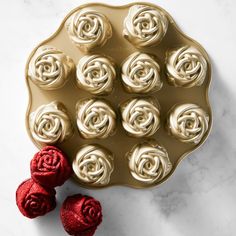 a gold plate with red roses on it next to some chocolates in the shape of hearts