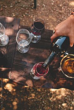 a person pours wine into glasses on a picnic table