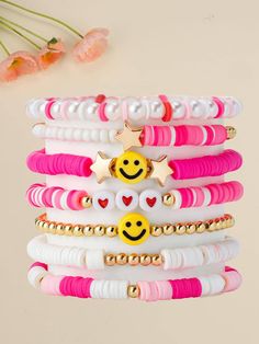 a stack of bracelets with smiley faces and stars on them, sitting next to flowers