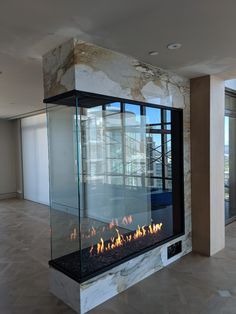 a modern fireplace in the middle of an empty room with large windows and glass doors