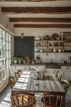 a kitchen table with chairs and plates on top of it in front of an open window