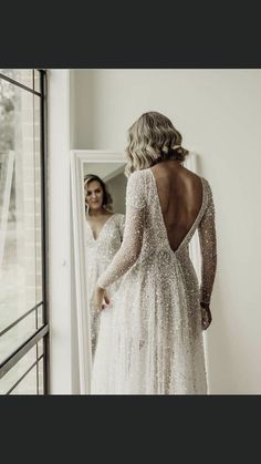 a woman standing in front of a mirror wearing a dress with sequins on it