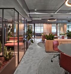 an office with glass walls and plants in the center, along with red chairs on either side